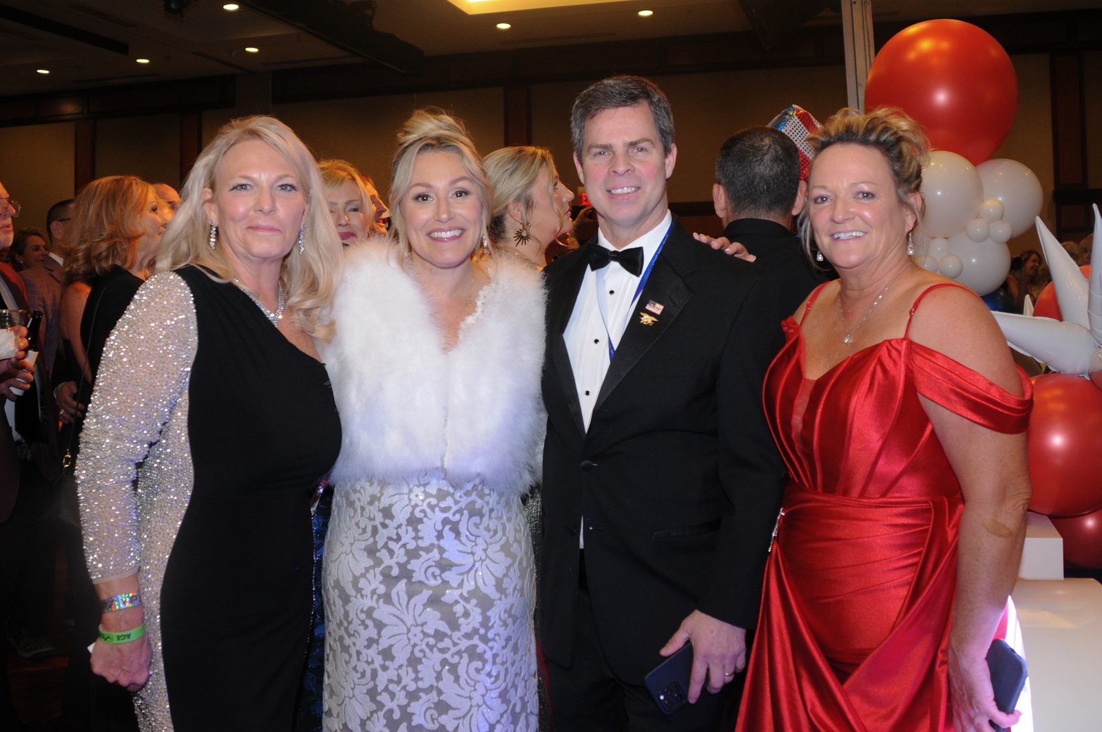 Four elegantly dressed guests posing in the ballroom