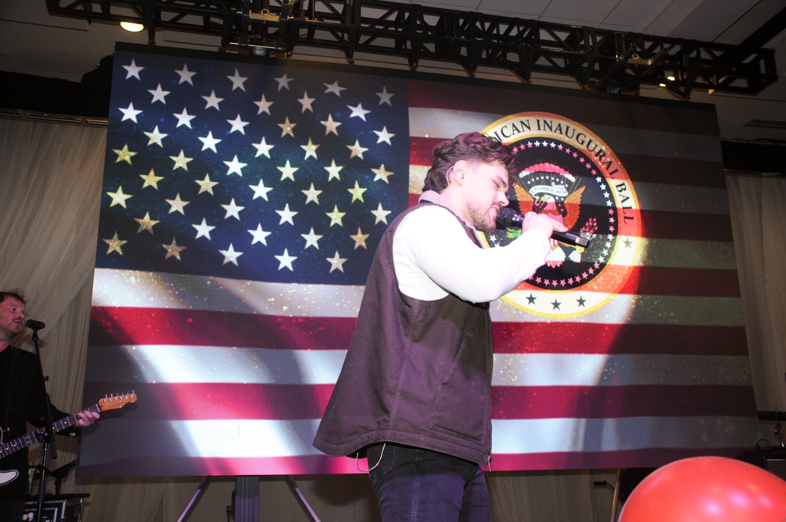 Singer performing in front of a giant American flag stage screen